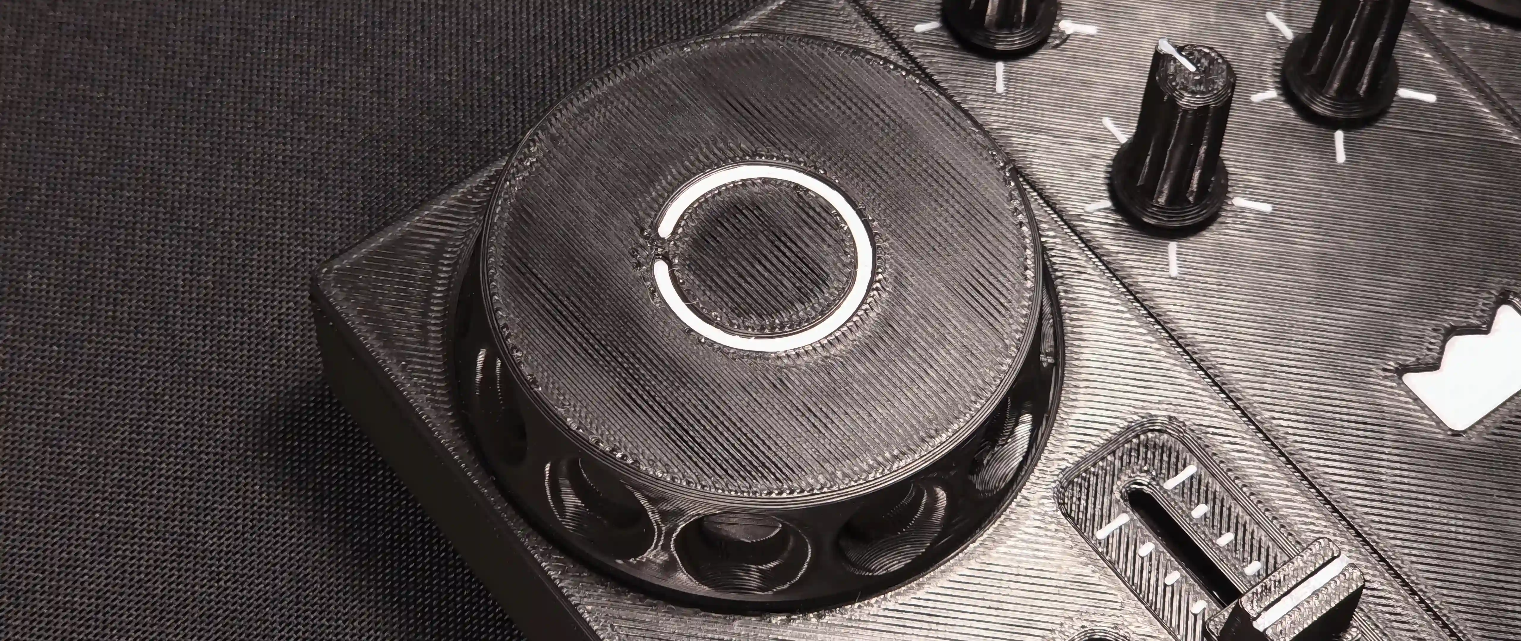 Close-up of a jog wheel, with the printed layer lines visible and the knobs beside it