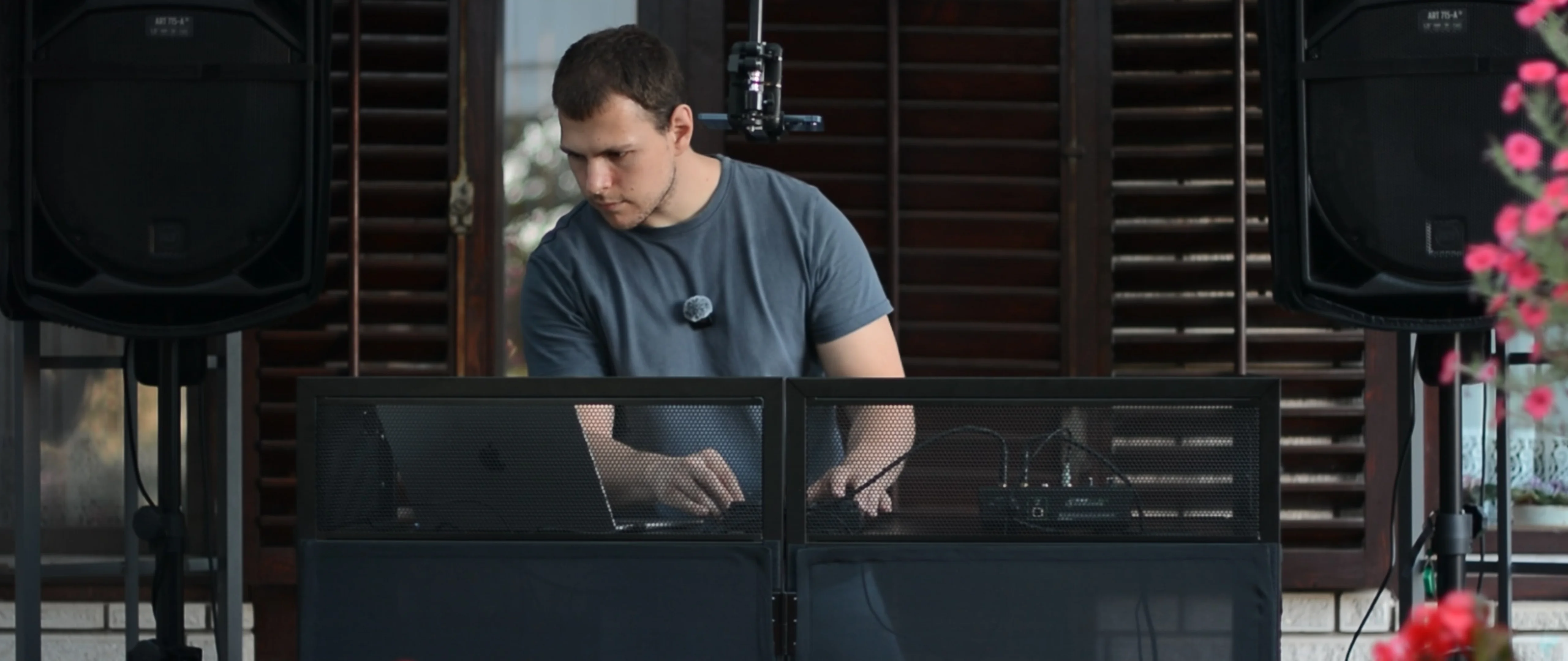 DJ Tweety mixing behind a DJ booth with a laptop, between two large speakers